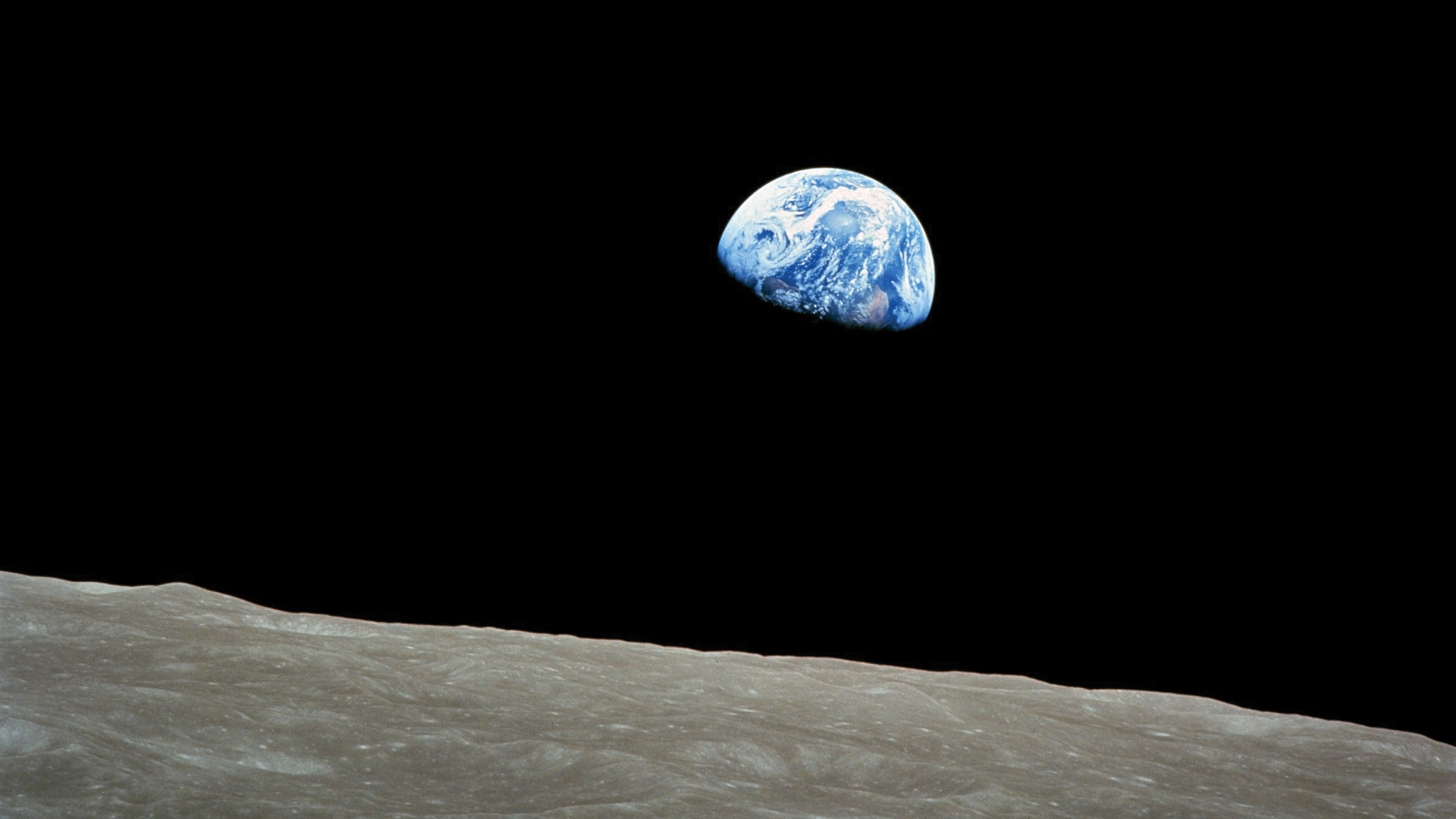 Photo of Earth taken from outer space, with the lunar surface in the foreground