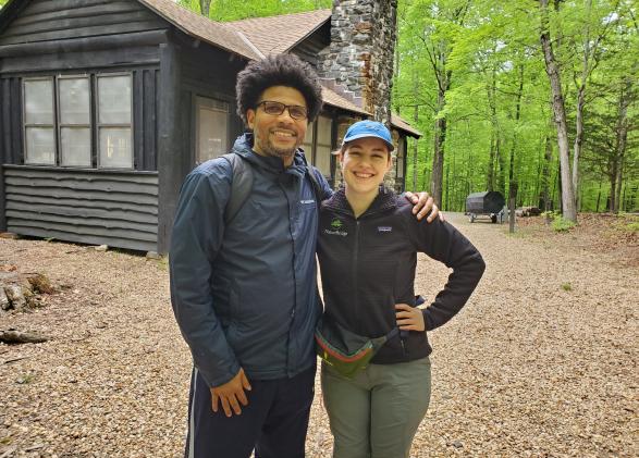 Jason Brown and NatureBridge Educator Raye pose in front of a cabin.