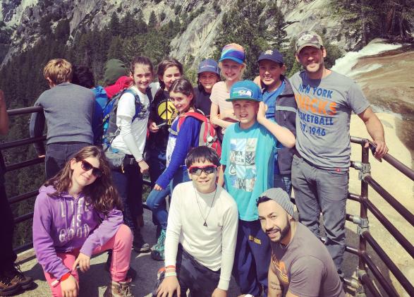 students and teachers outside at Yosemite, in front of waterfall sunny day