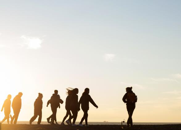 Students walk on Rodeo beach during sunset.