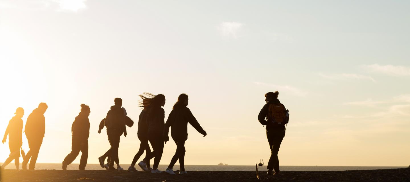 Students walk on Rodeo beach during sunset.