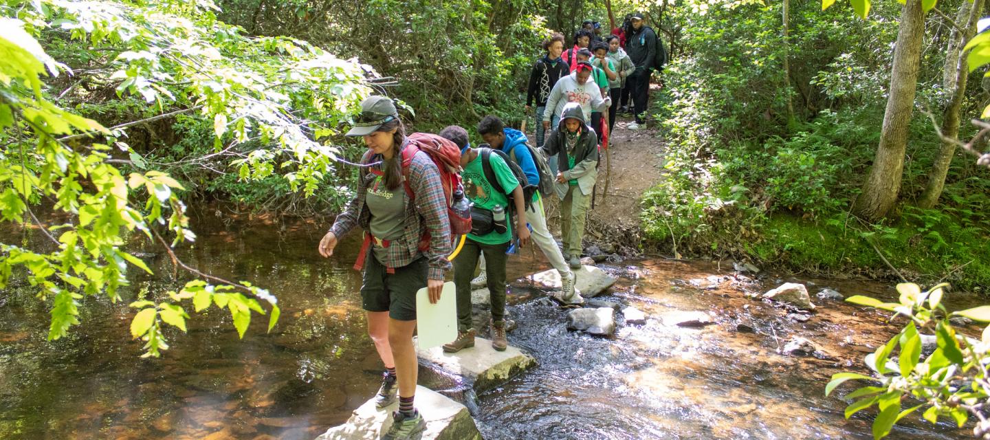 NatureBridge students hike across a stream in Prince William Forest Park.