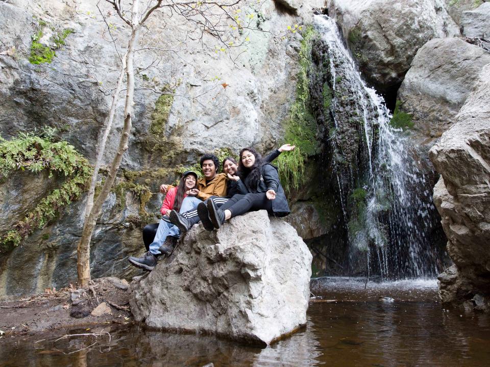 students on rock next to waterfall