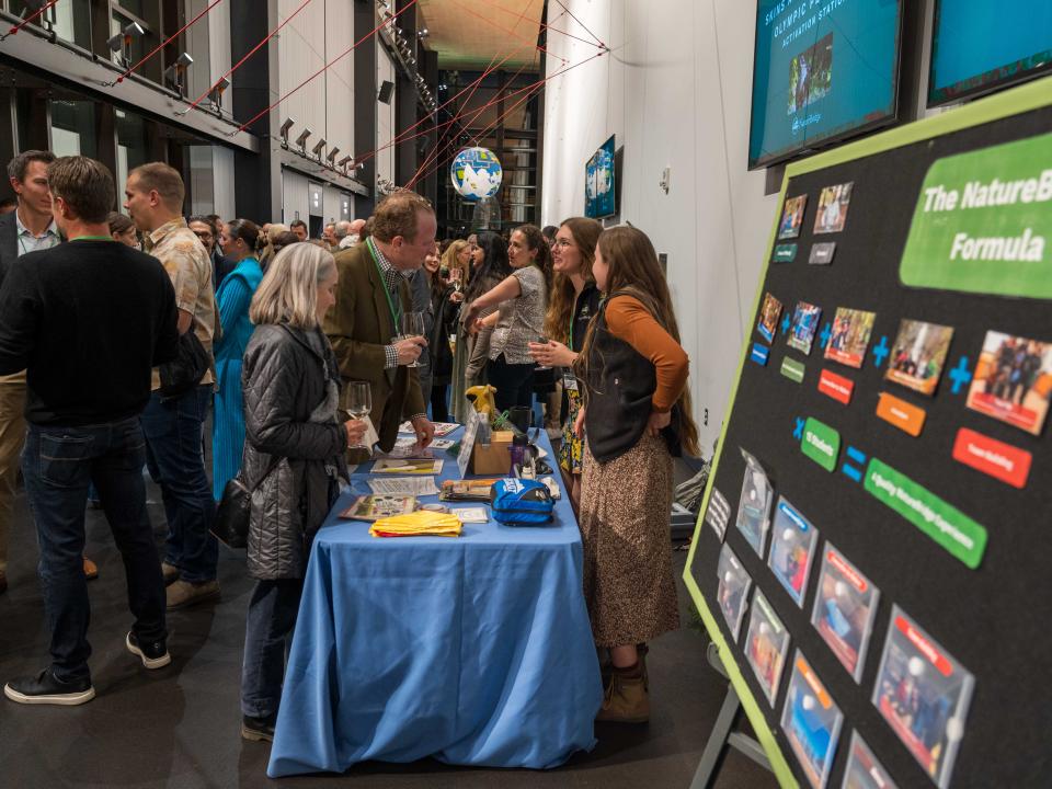 Guests mingling and talking with NatureBridge educators at an activity table during the reception