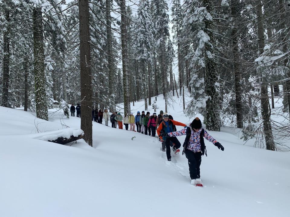 A NatureBridge learning group exploring the snowy landscape using snowshoes to help keep them from sinking into the snow