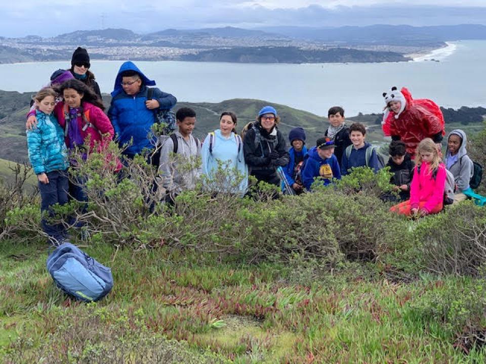 group of students hiking at Hill 88 with city of San Francisco in the background 