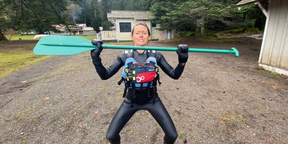 Chelsea wearing a wetsuit and holding a paddle 